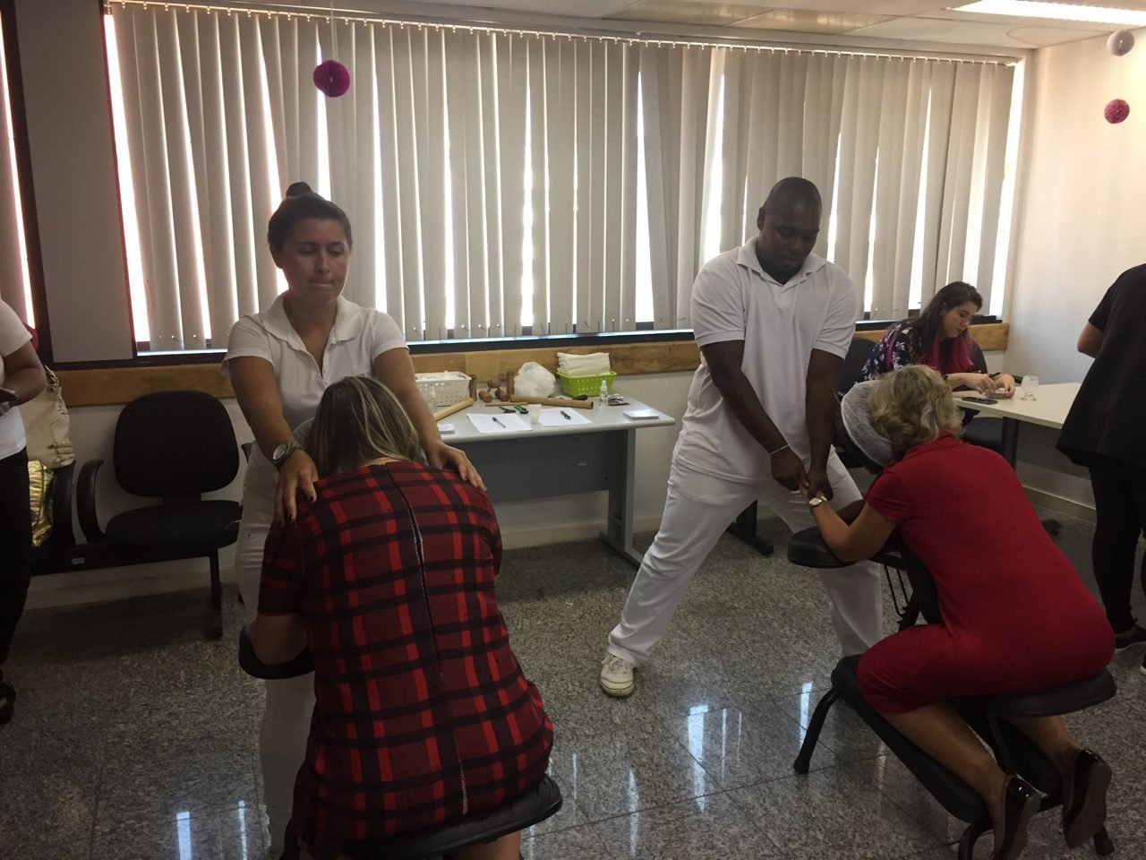 Participantes recebendo quick massage em área de bem-estar durante congresso, no Rio de Janeiro — quick massage para congressos e palestras corporativas.